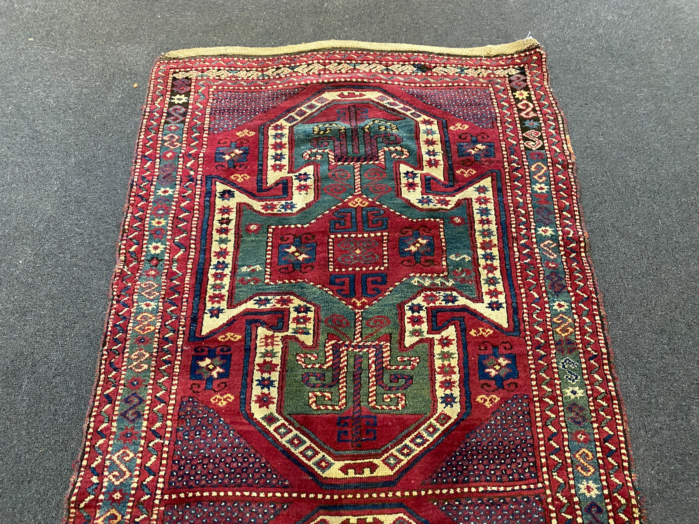 An antique Kazak red ground rug, 280 x 120cm